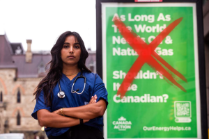 Photo of a doctor standing in front of fossil fuel ad