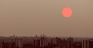 View of Toronto at sunset with a reddish sun and hazy skies caused by wildfire smoke