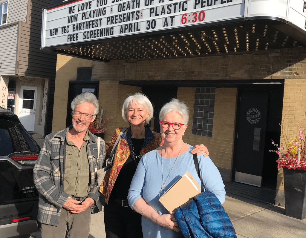 Dr. Donald Cole pose avec deux autres personnes devant un cinéma