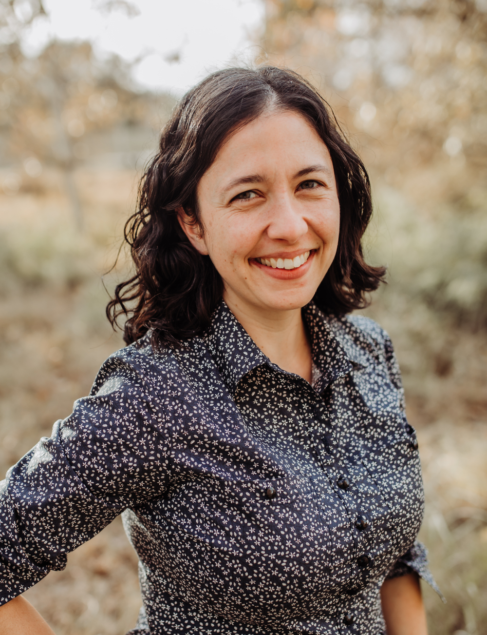 Image de profil d’Anjali Helferty souriant, portant une chemise boutonnée noire et blanche