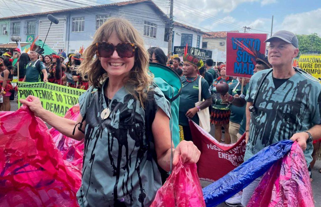 Nola Poirer and Dr. Joe Vipond in scrubs holding deflated inflatable lungs at a COP30 outdoor rally